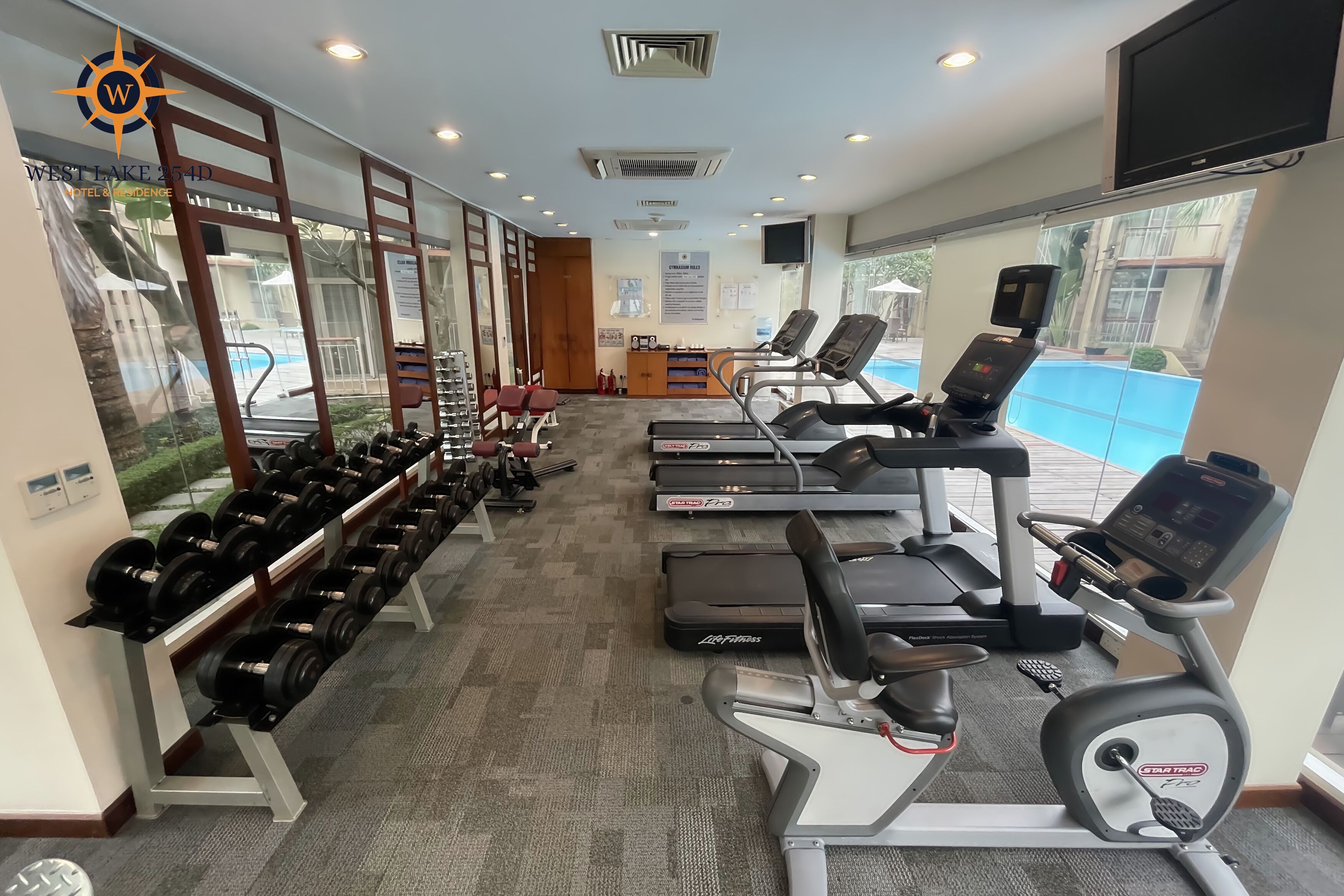 A gym with treadmills, dumbbells, and exercise equipment.
