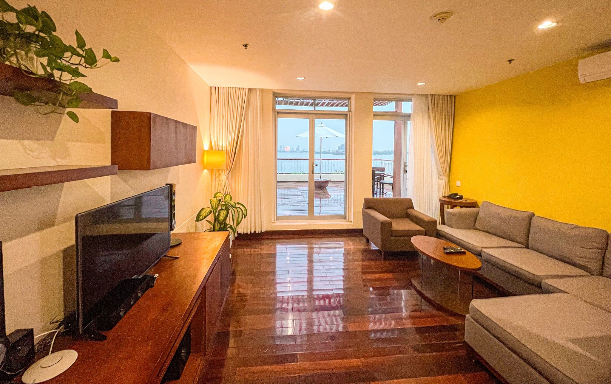 Una sala de estar moderna con un televisor de pantalla plana, un sofá, una mesa de centro y una planta en maceta.