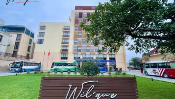 Entrada de hotel con un cartel que dice "Wilque", rodeada de vegetación y edificios modernos.