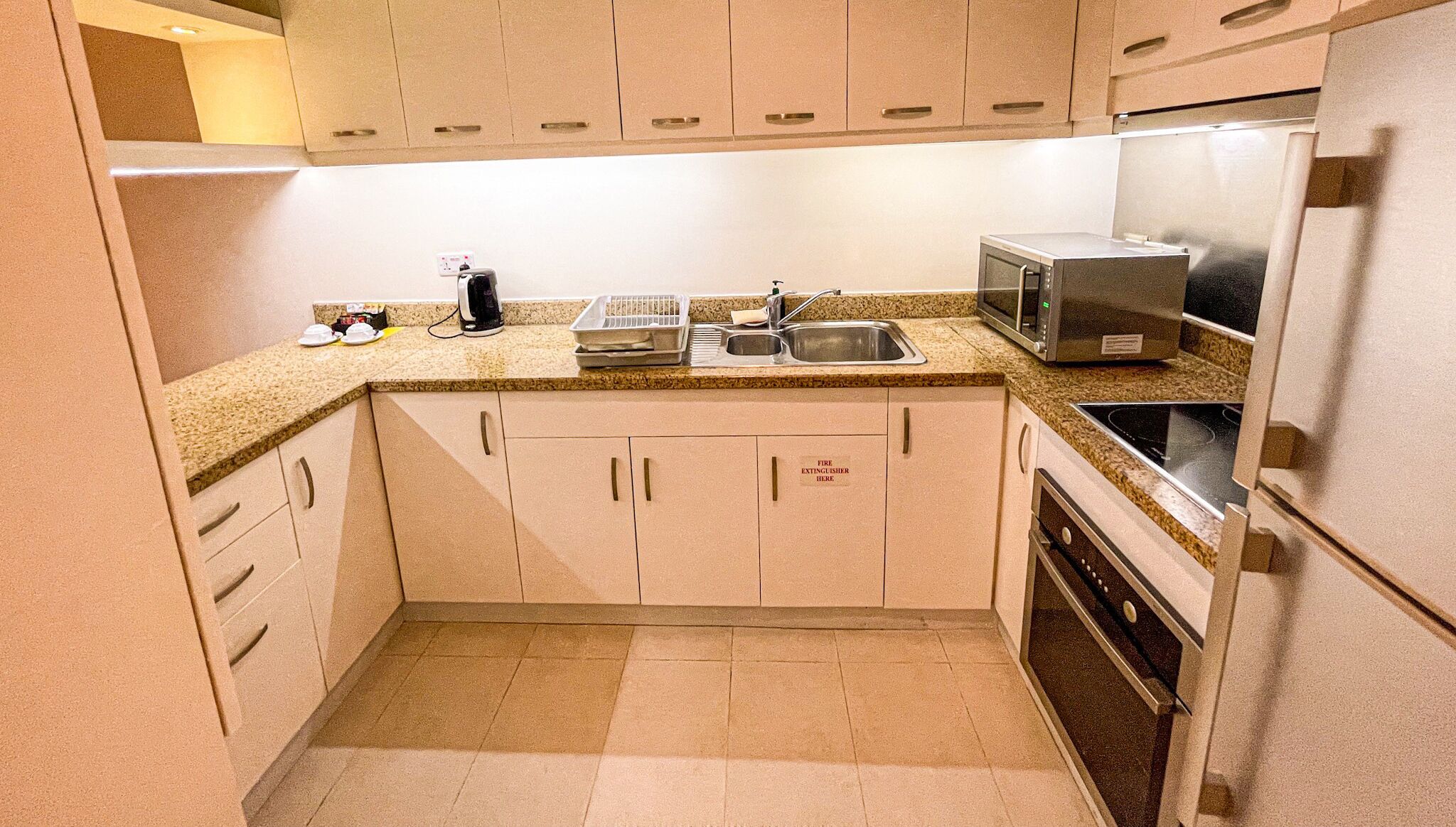 A compact kitchen with a microwave, stove, and sink.