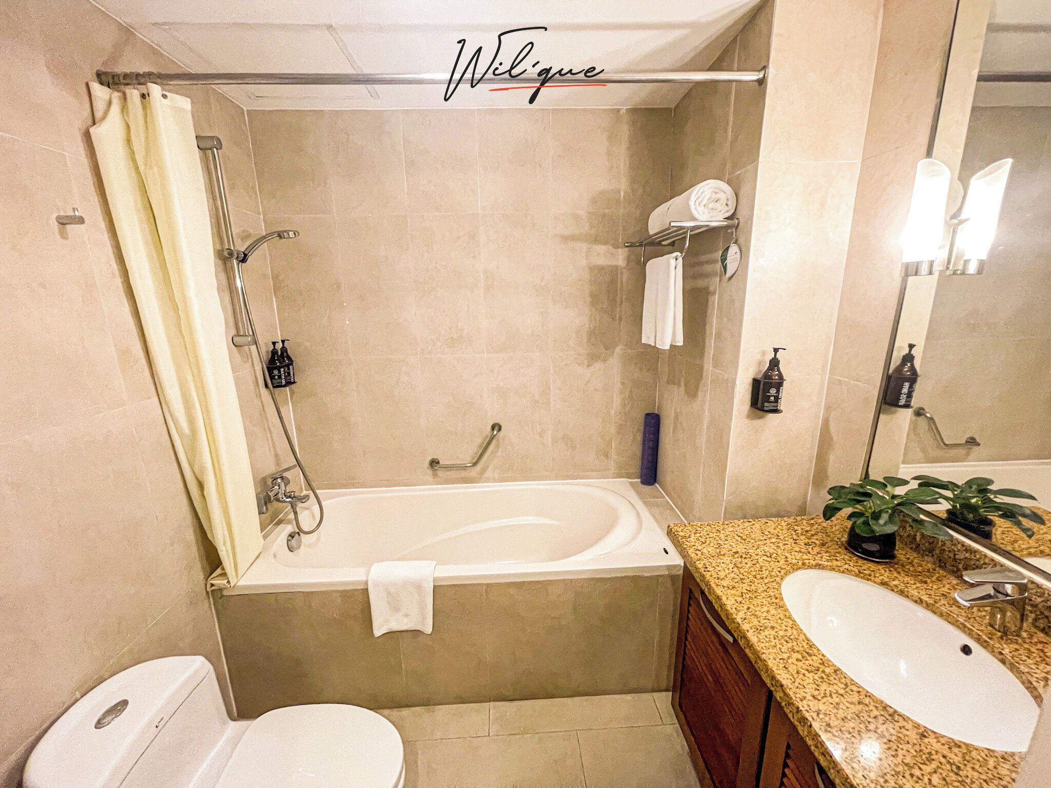 A bathroom with a bathtub, toilet, sink, and a mirror.