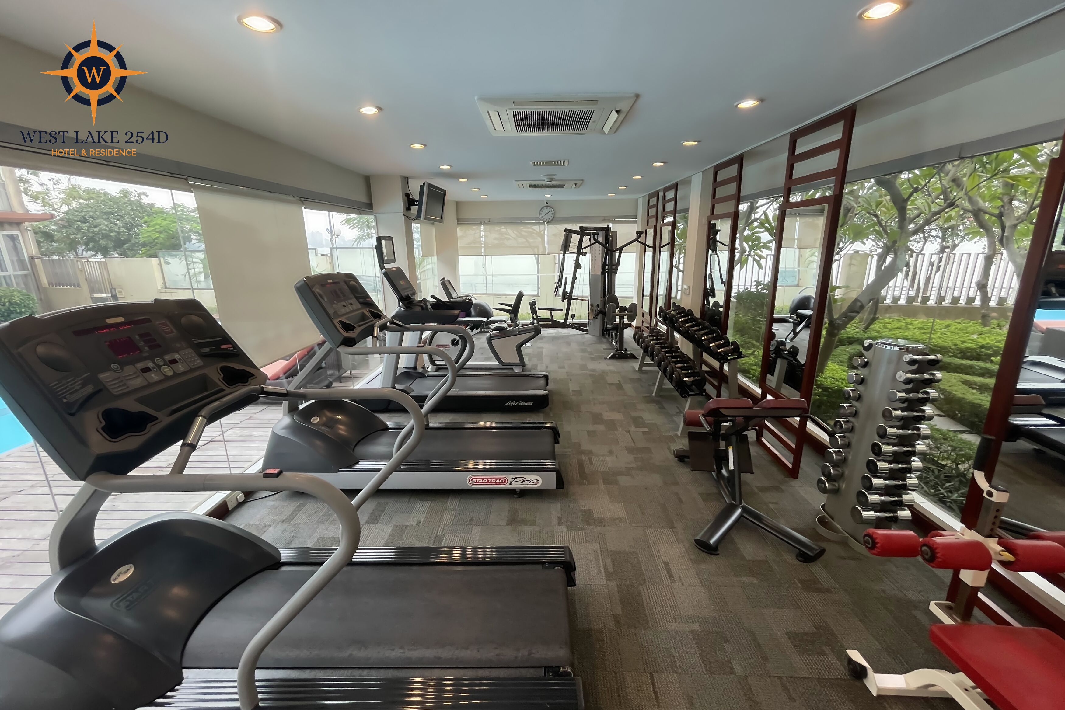 A gym with treadmills, weight machines, and dumbbells.