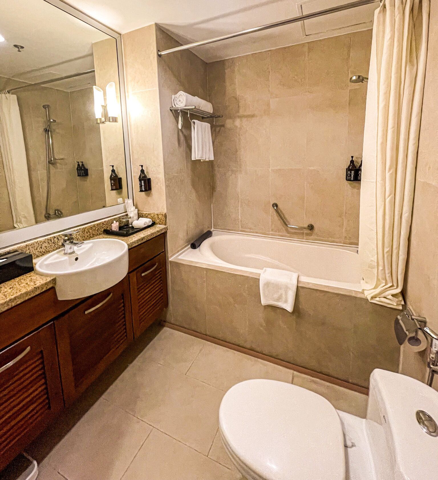 A modern bathroom with a sink, mirror, vanity, bathtub, and toilet.