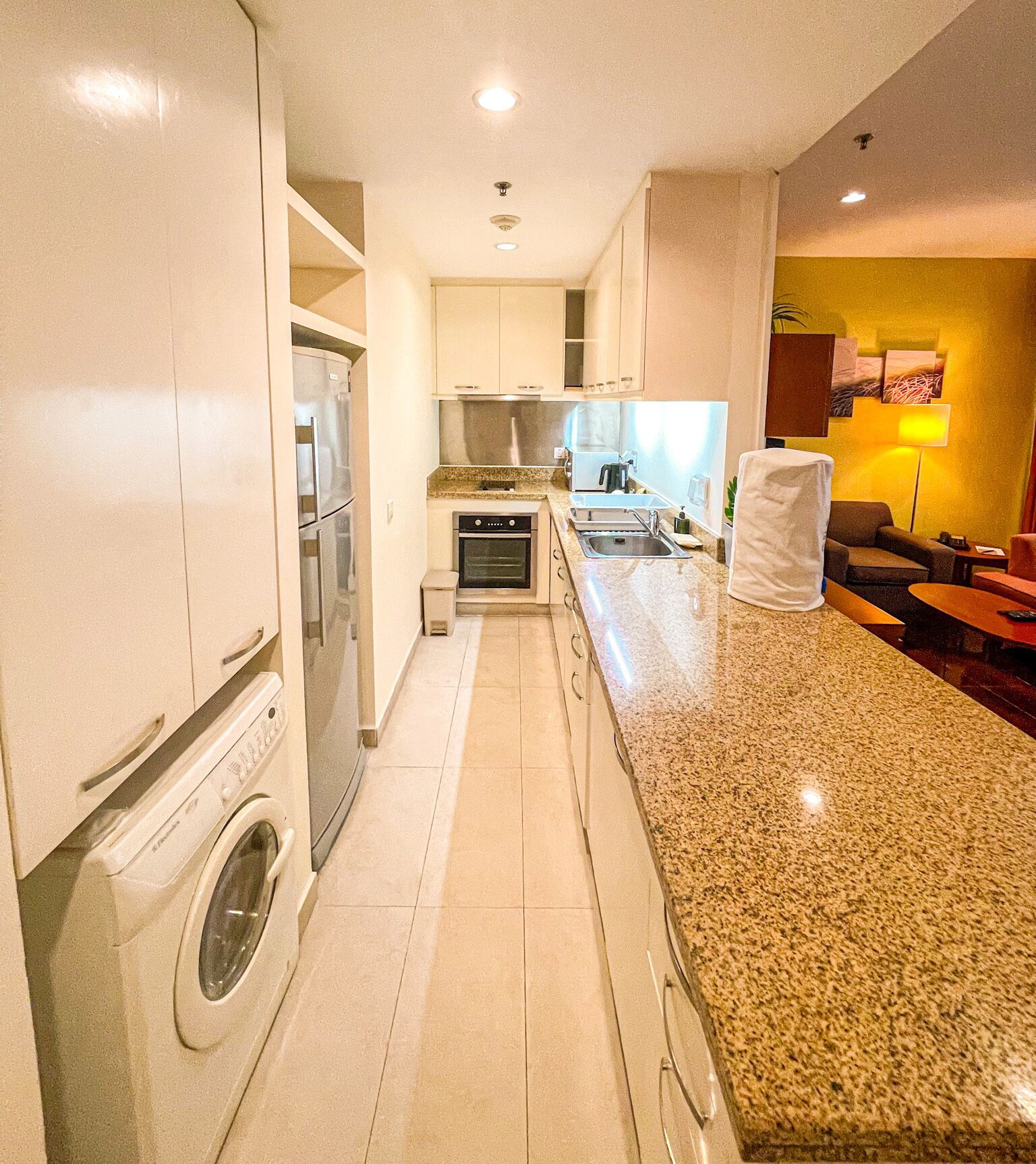 Een kleine keuken met een wasmachine, een fornuis en een spoelbak.
