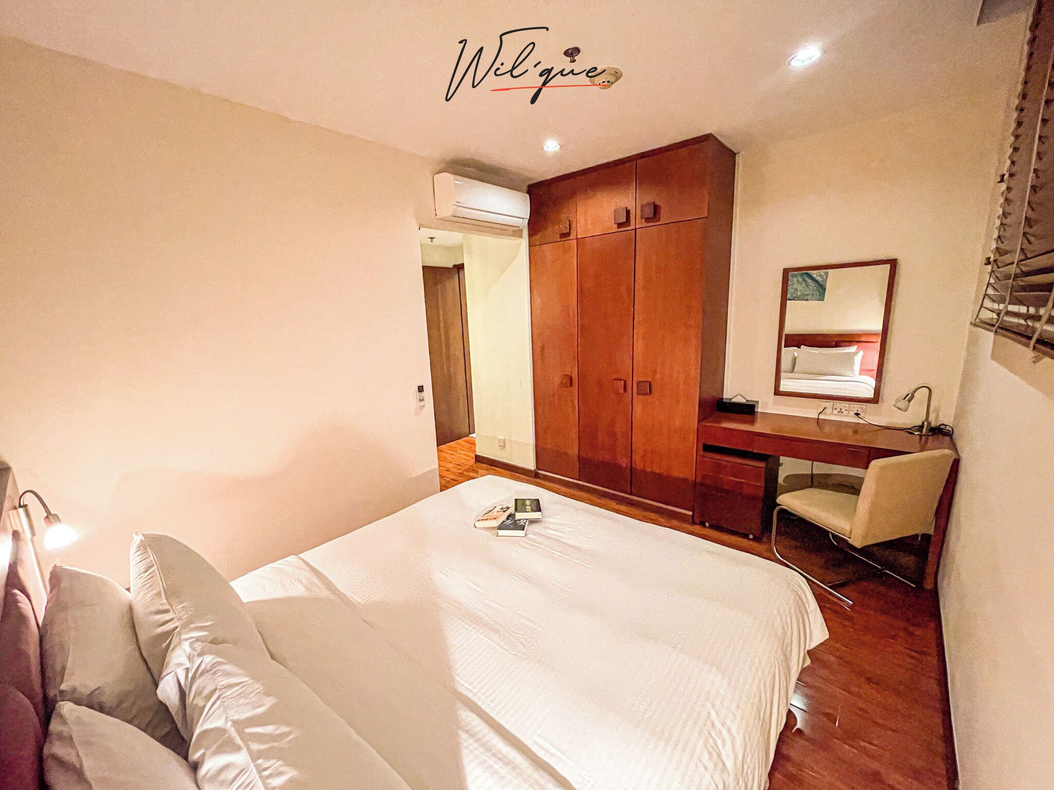 A bedroom with a bed, a desk, a chair, a wardrobe, and a mirror.