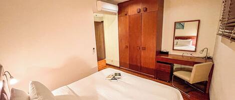 Un dormitorio con cama, escritorio, silla, armario y espejo.