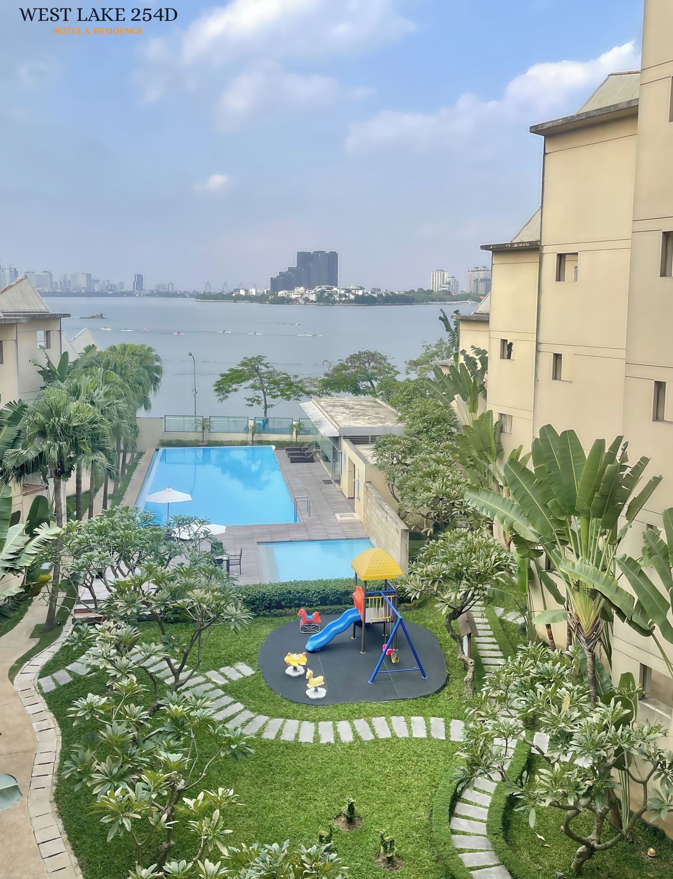 A residential area with a swimming pool, a playground, and a view of a body of water.