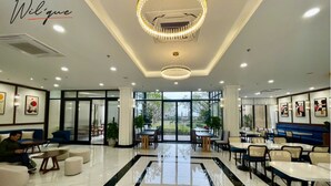 Un moderno vestíbulo de hotel con piso de mármol, espacios para sentarse y ventanas amplias que ofrecen vistas al exterior.