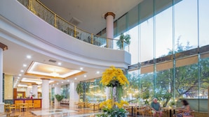 A spacious lobby with a reception desk, seating areas, and large windows offering views of greenery. - Nha Trang Lodge Hotel (Nha Trang)