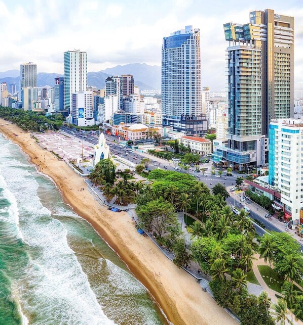A coastal cityscape with a beach, high-rise buildings, and a mix of commercial and residential structures.