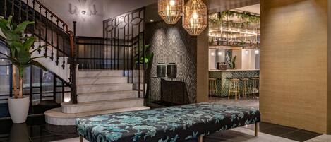 Un vestíbulo moderno con una escalera, un mostrador de recepción y una zona de bar.
