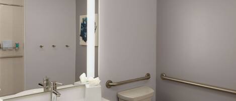 Un baño moderno con un lavamanos blanco, un inodoro y un pasamanos.