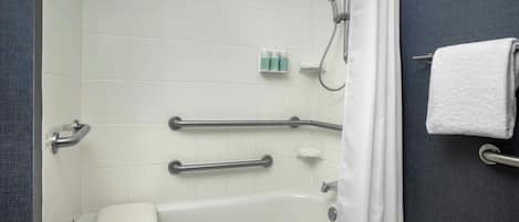 A bathroom with a white bathtub, grab bars, a shower curtain, and a towel rack.