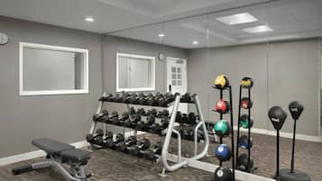 A gym with dumbbells, a bench, and exercise balls.