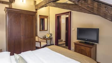 Una camera da letto con un letto, un armadio in legno, televisione e un tavolino con un bollitore.