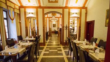 Une salle à manger d’hôtel avec plusieurs tables, des chaises et un sol à motifs à carreaux.