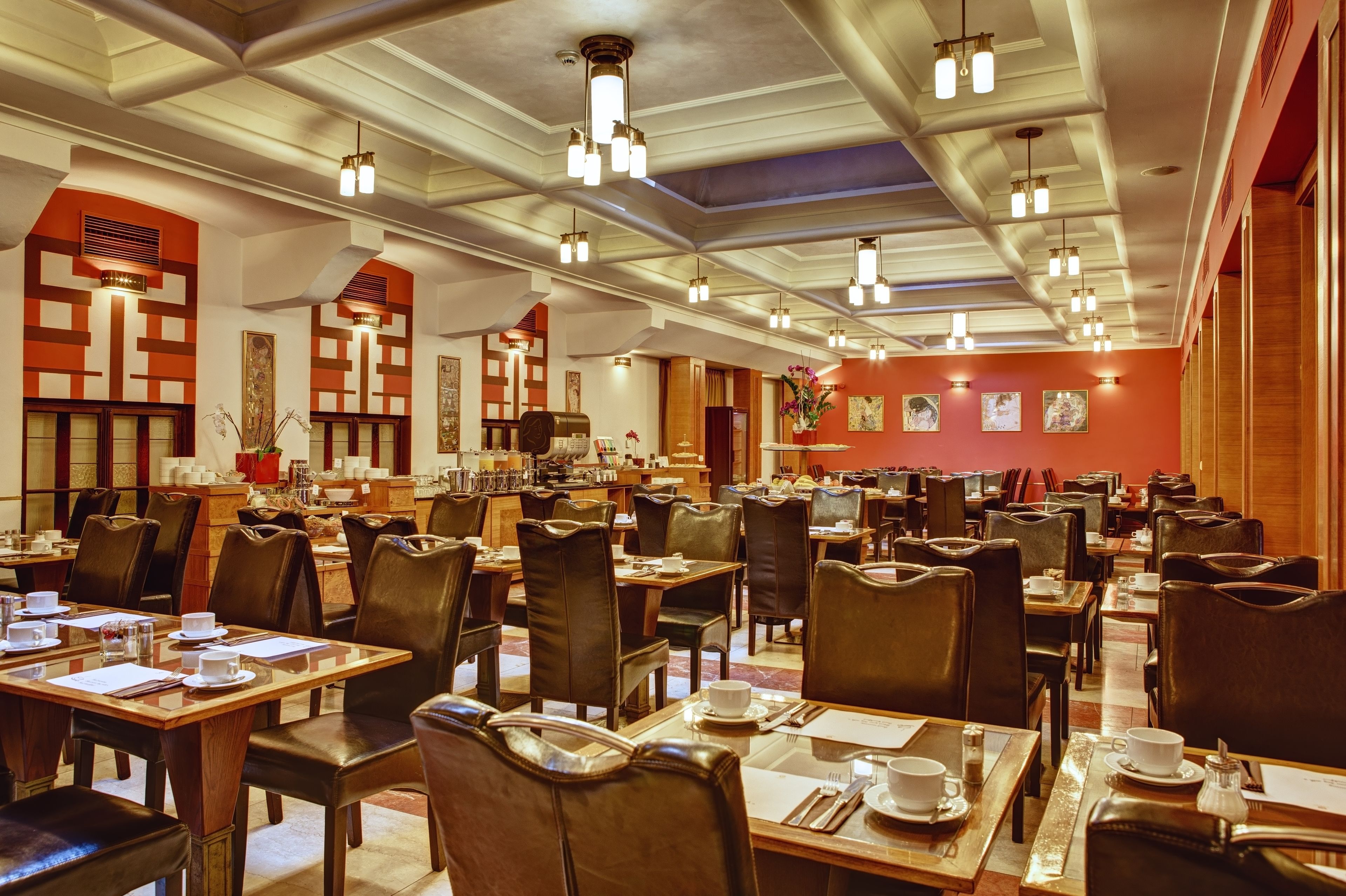 Un vaste espace dédié à la salle à manger, comprenant plusieurs tables et chaises, des luminaires au plafond et des œuvres d’art accrochées aux murs.