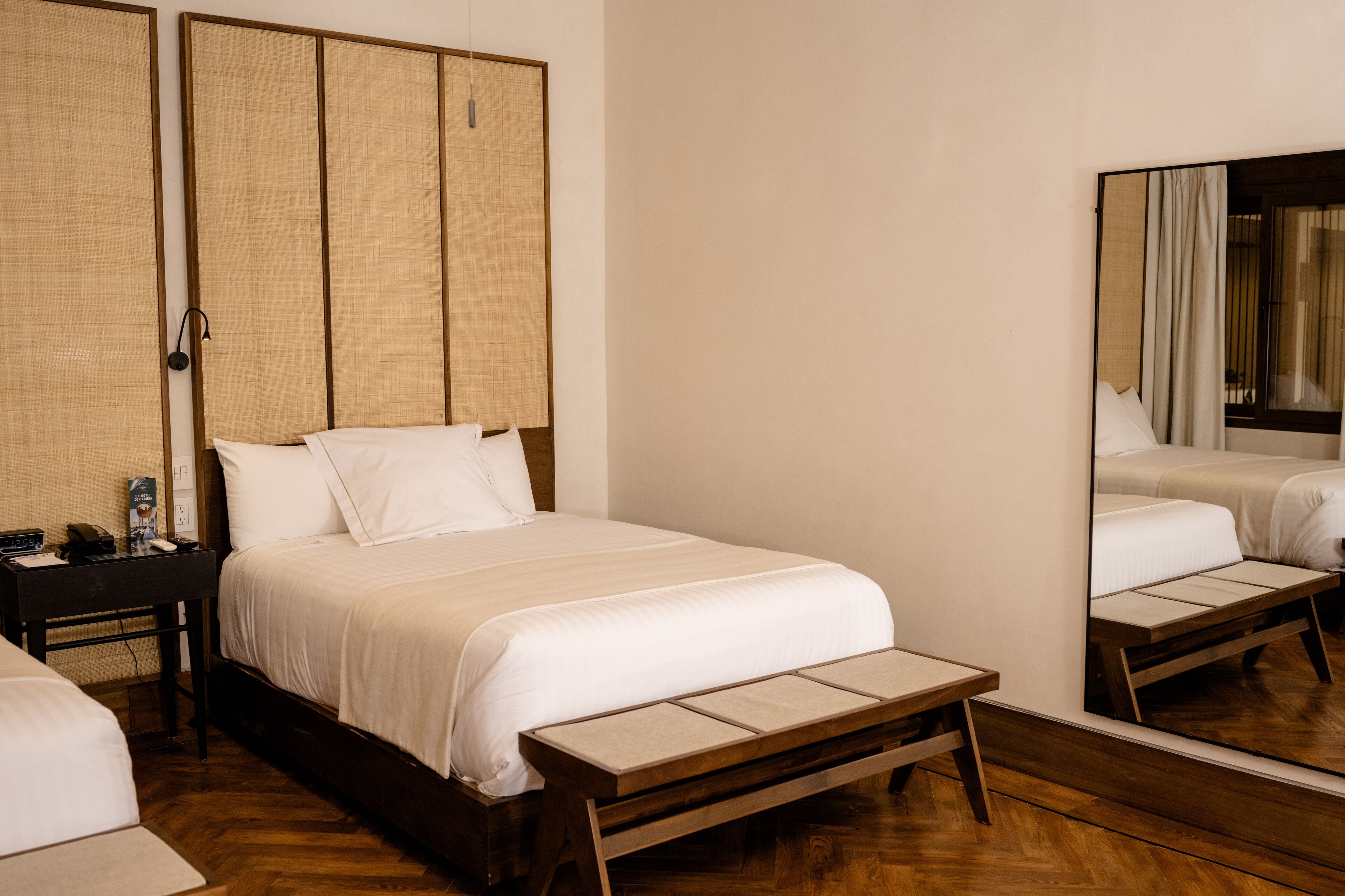 Una habitación de hotel con cama, mesita de noche y espejo.
