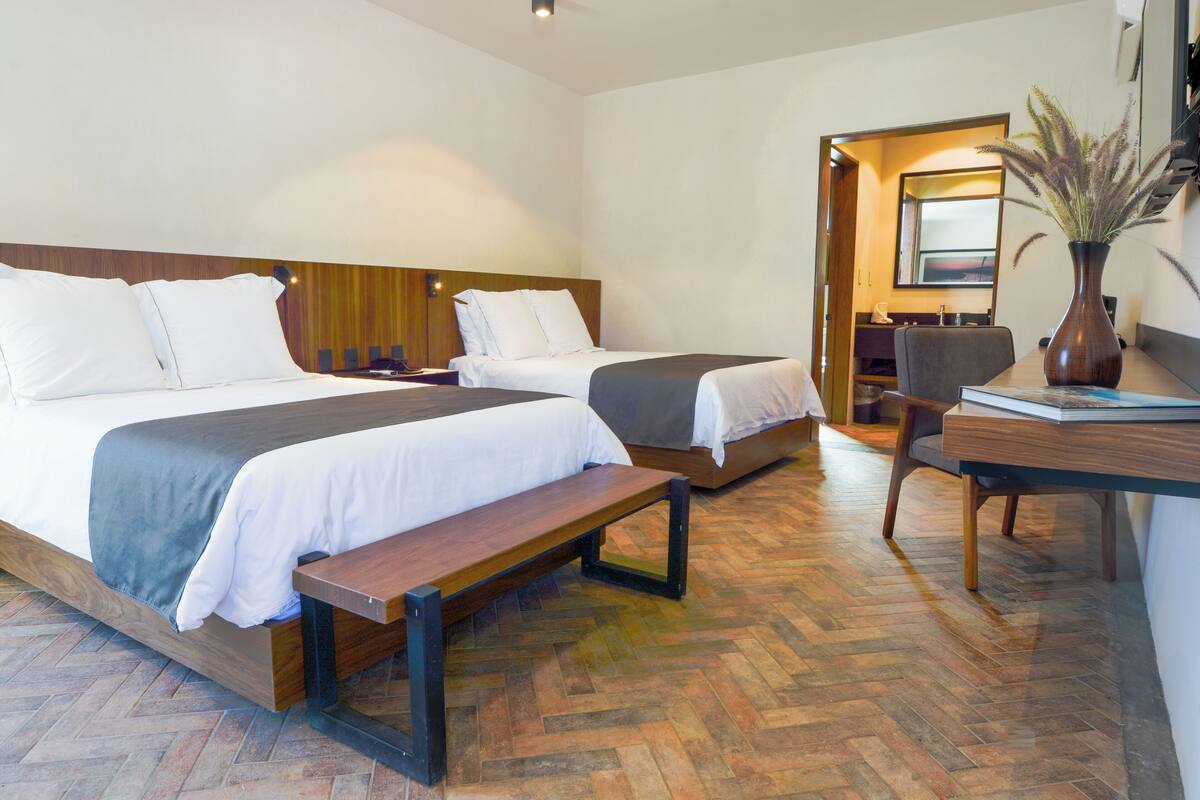 Une chambre d’hôtel avec deux lits, un bureau et une chaise.