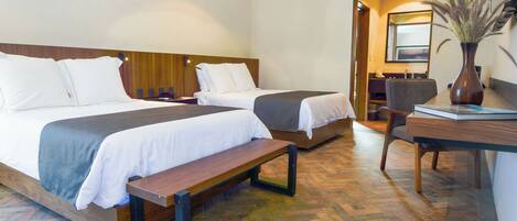 A hotel room with two beds, a desk, and a chair.