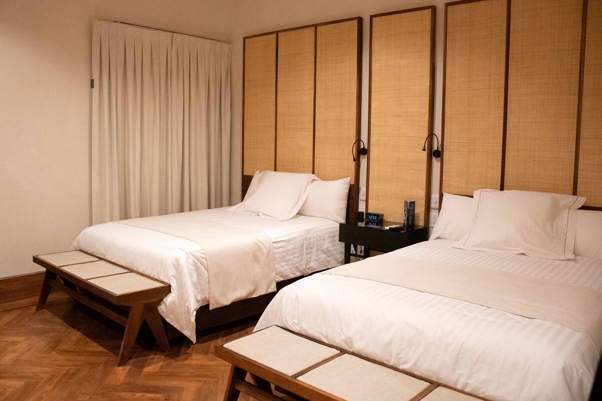 Une chambre d’hôtel avec deux lits, un plancher en bois et un paravent de style japonais traditionnel.