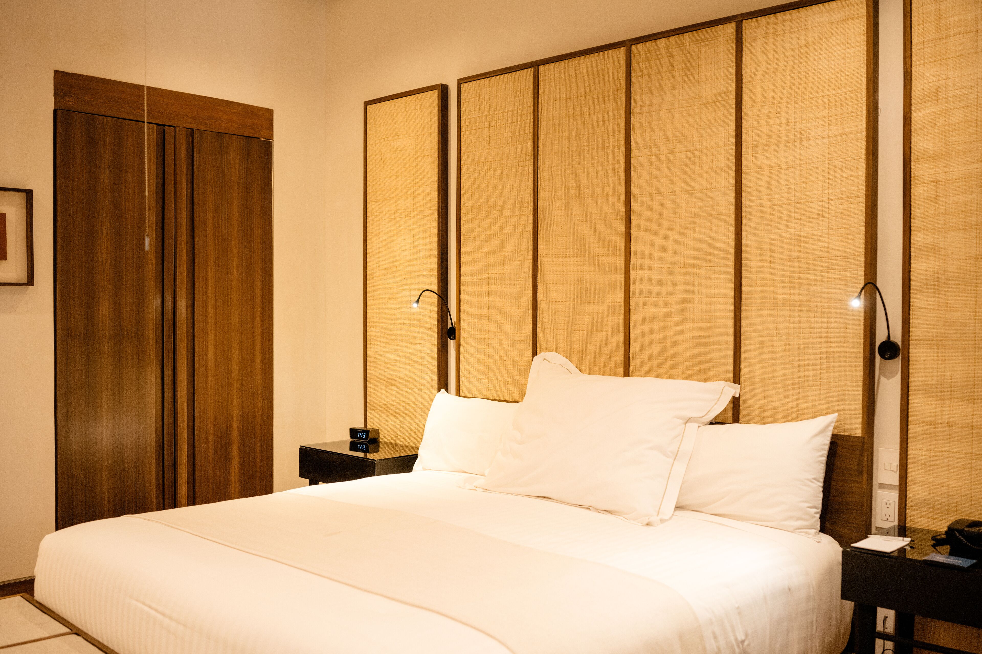 A hotel room with a large bed, wooden wardrobe, and a traditional sliding door.