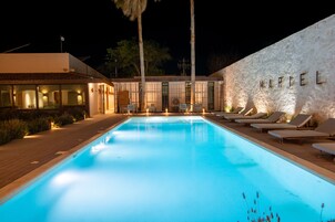 Una piscina al aire libre, sombrillas, sillones reclinables de piscina