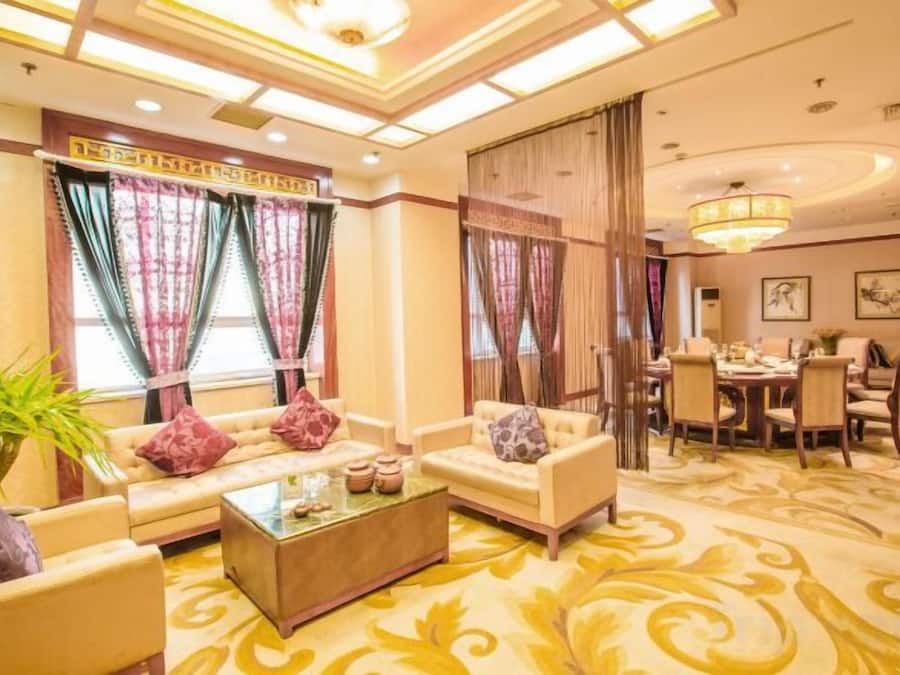 A hotel lobby with sofas, a coffee table, and a dining area with chairs and a table.