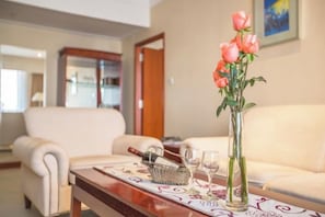 A living room with a sofa, a coffee table with a vase of flowers, and a framed picture on the wall.