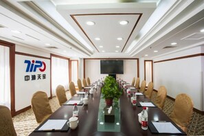 Een vergaderruimte met een lange tafel, stoelen, een televisie en een logo op de muur.