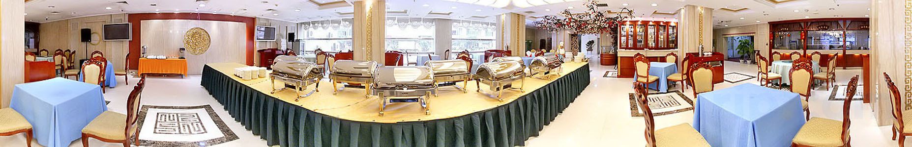 En festsal med runde borde, stole og et buffetbord.