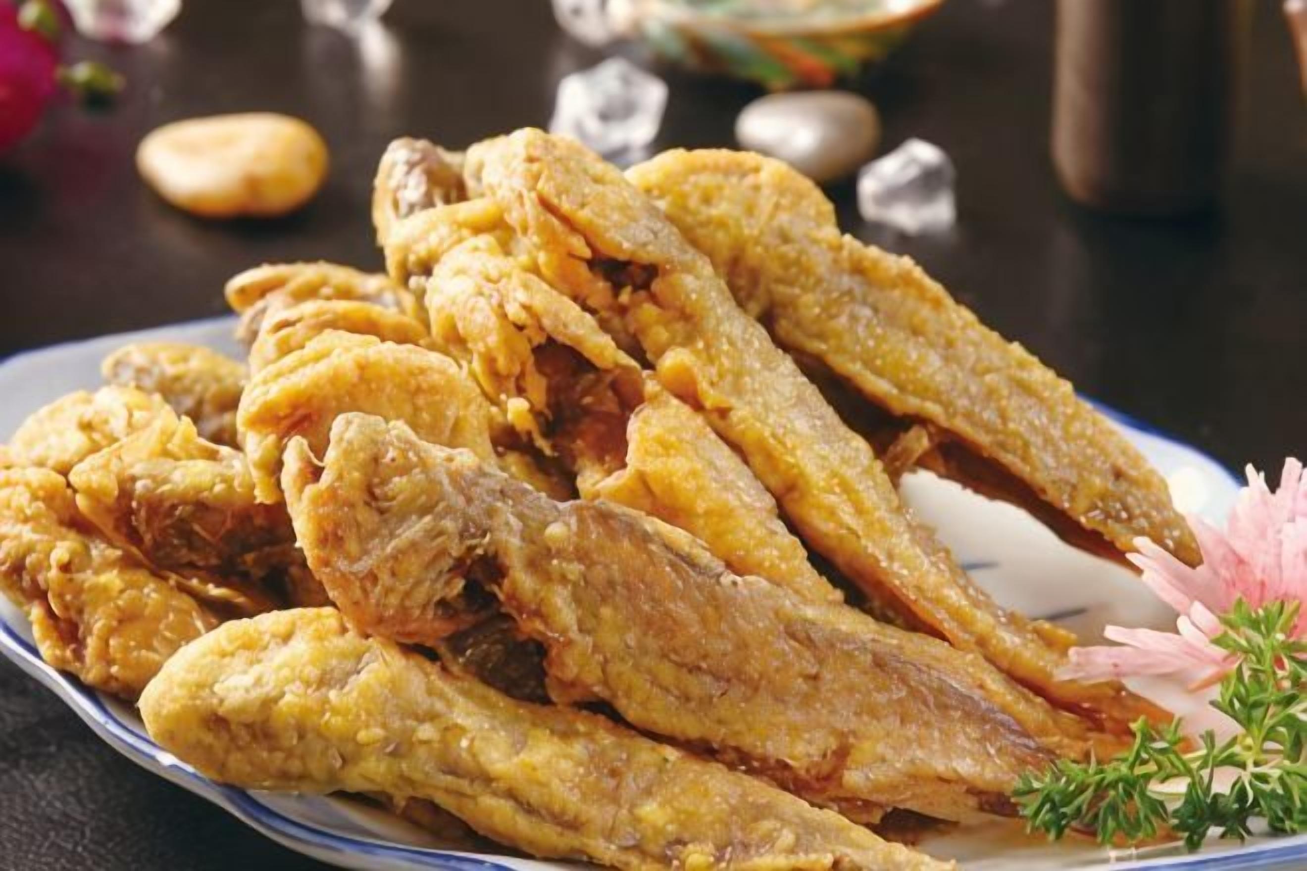 A plate of fried fish with a garnish.
