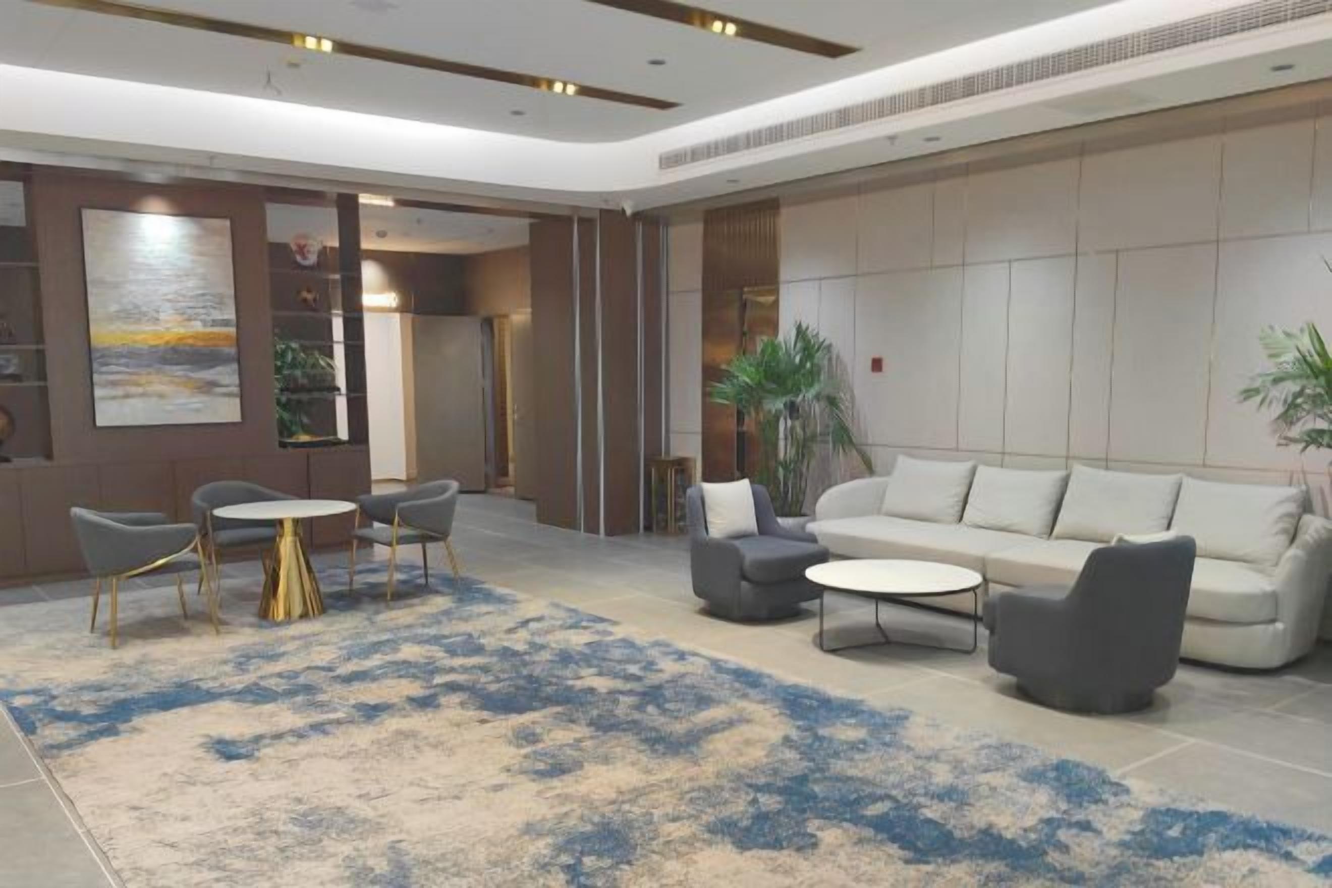 A spacious lobby with a large sofa, a coffee table, and a seating area with chairs.