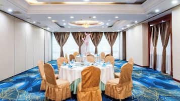Un salón de conferencias con una mesa redonda, sillas y una alfombra azul con motivos florales.