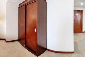 A corner of a room with a wooden wardrobe and a white wall.