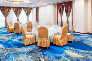A conference room with round tables and chairs, a blue carpet with a pattern, and curtains on the windows. - Shenyang Tianbao International Hotel (Zhongjie) (Shenyang)