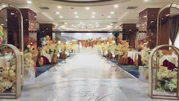 A banquet hall with a central aisle, tables on either side, and floral decorations.