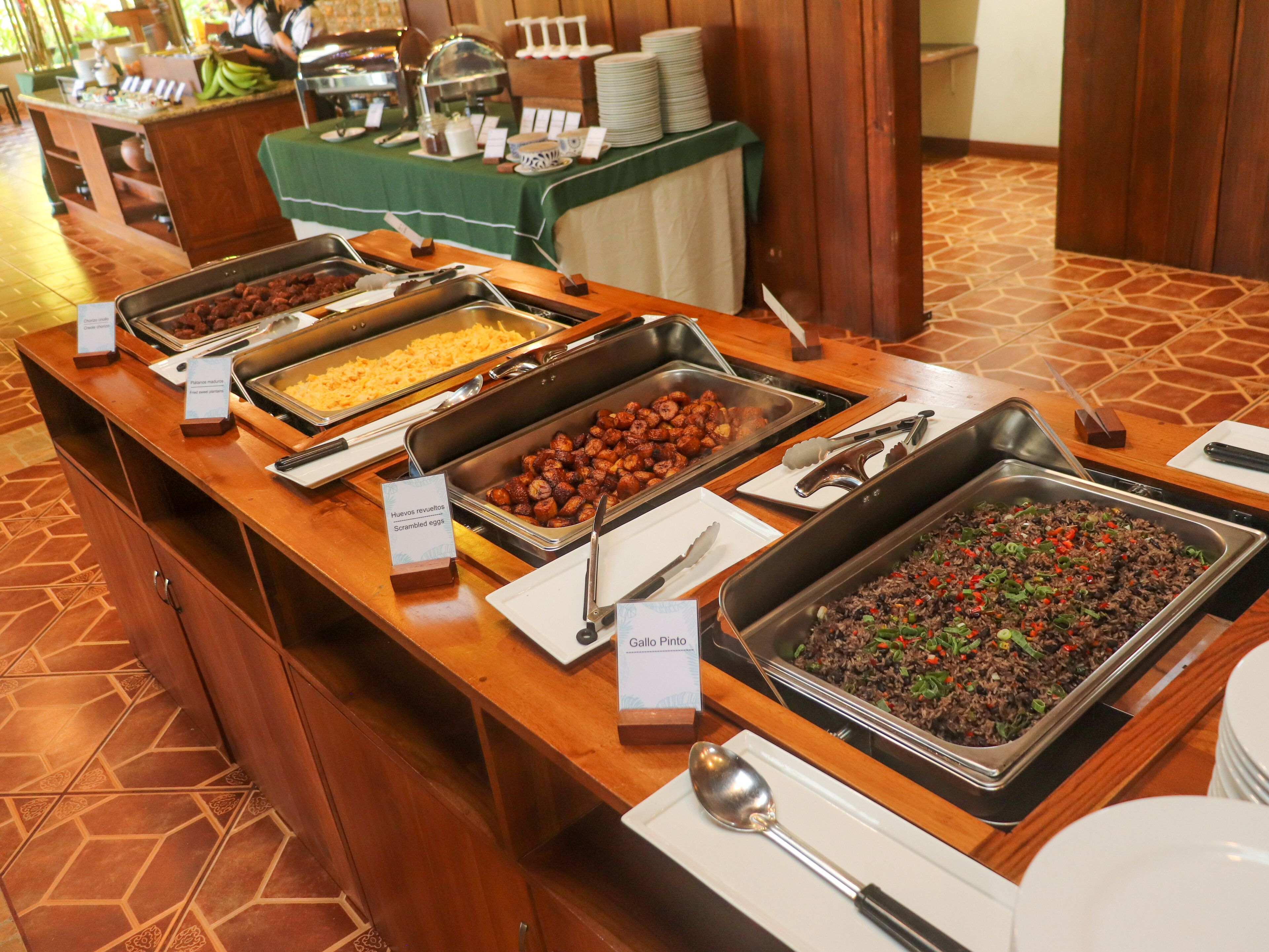 A buffet with various food options including scrambled eggs, queso fundido, and a black bean dish.
