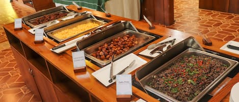 A buffet with various food options including scrambled eggs, queso fundido, and a black bean dish.