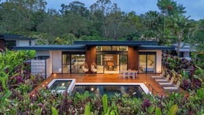 A modern house with a swimming pool, outdoor seating, and lush greenery. - Arenal Manoa & Hot Springs Resort (La Fortuna)