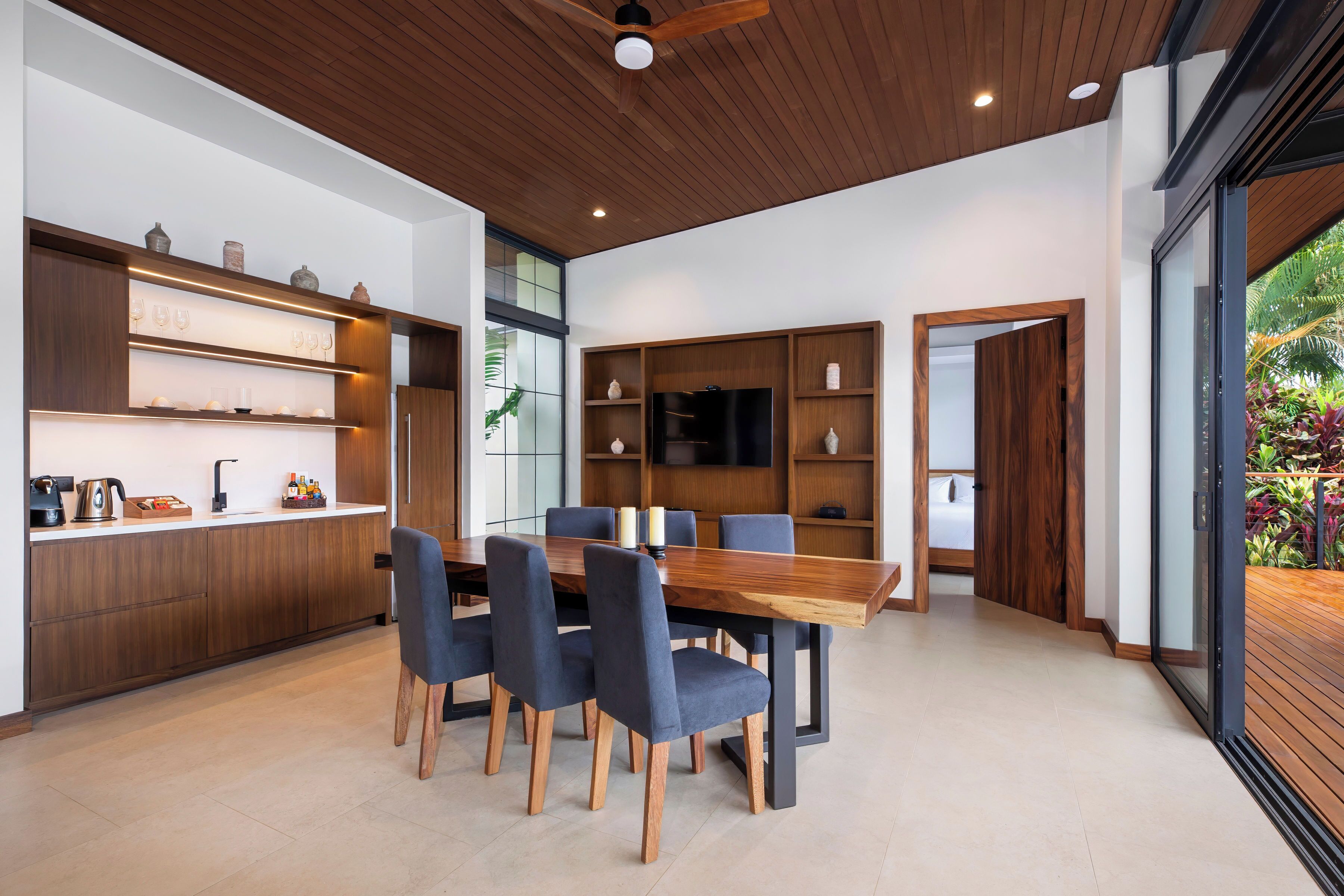 Una cocina moderna con armarios de madera, una mesa de comedor con sillas y un televisor empotrado.