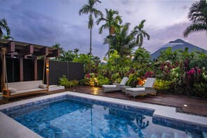 A pool area with lounge chairs, a wooden deck, and tropical plants. - Arenal Manoa & Hot Springs Resort (La Fortuna)