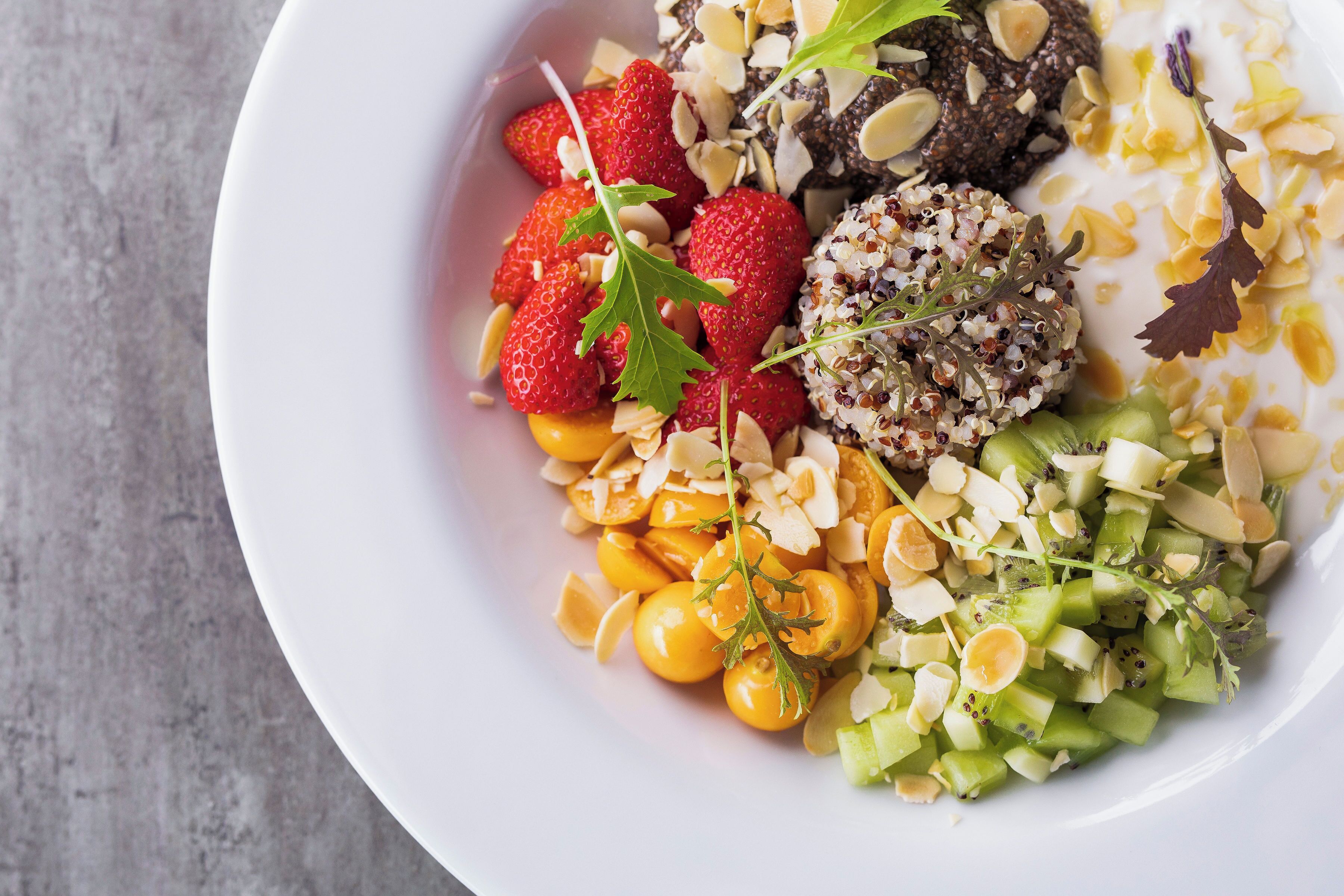 Eine Schüssel gemischter Obstsalat mit Erdbeeren, Kiwis und anderem Obst.