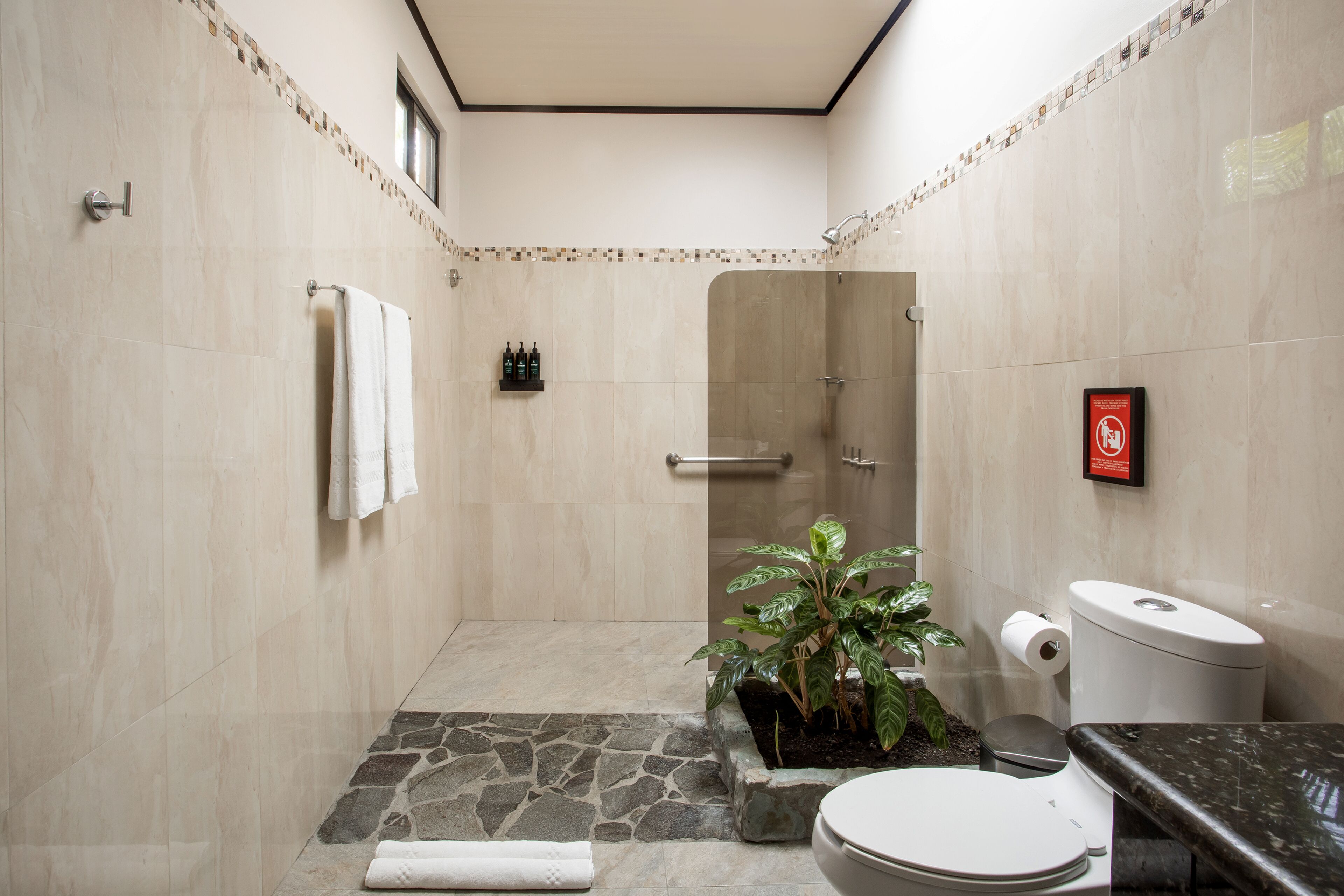 A modern bathroom with a shower, toilet, and sink.