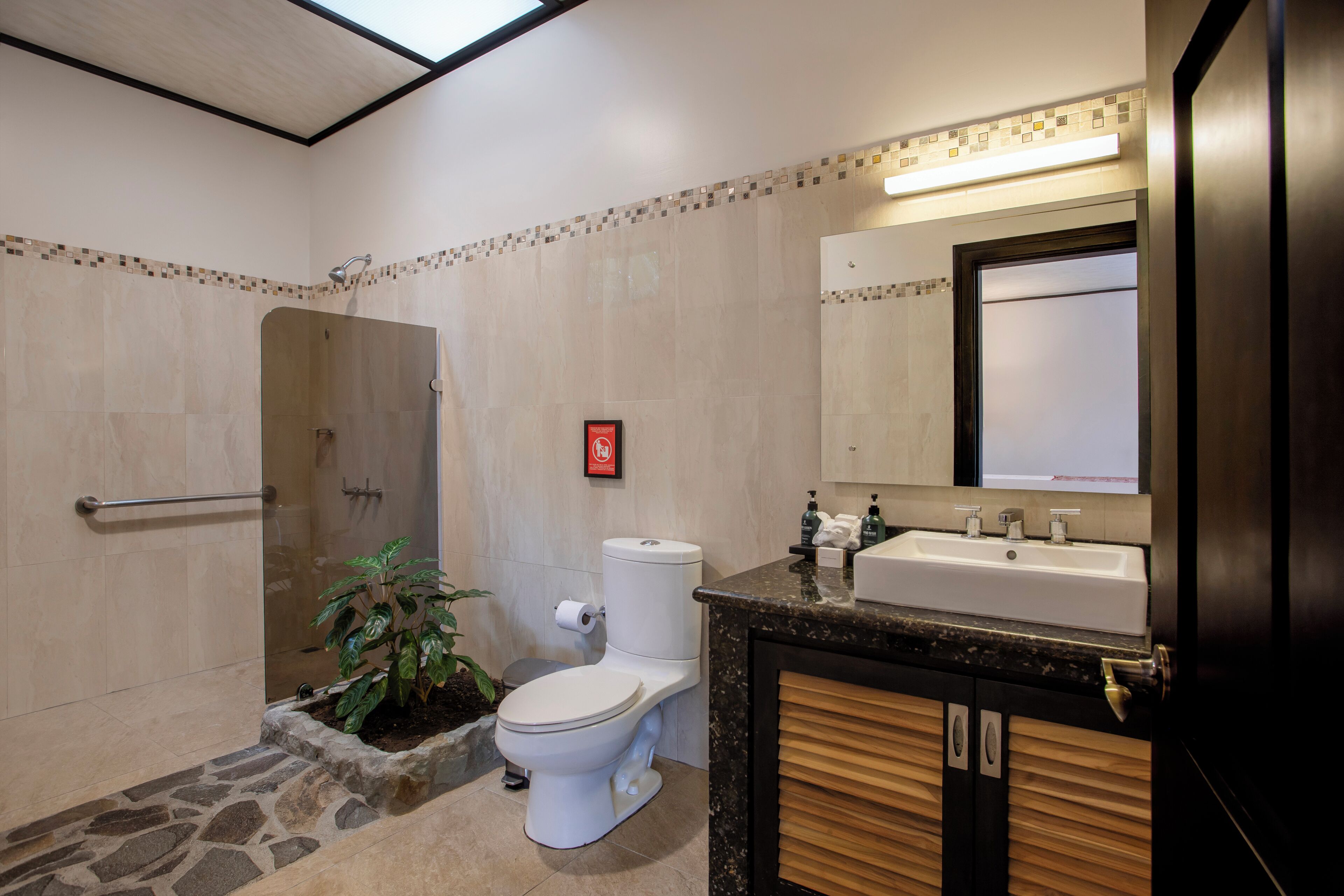 A modern bathroom with a shower, toilet, sink, and a large mirror.