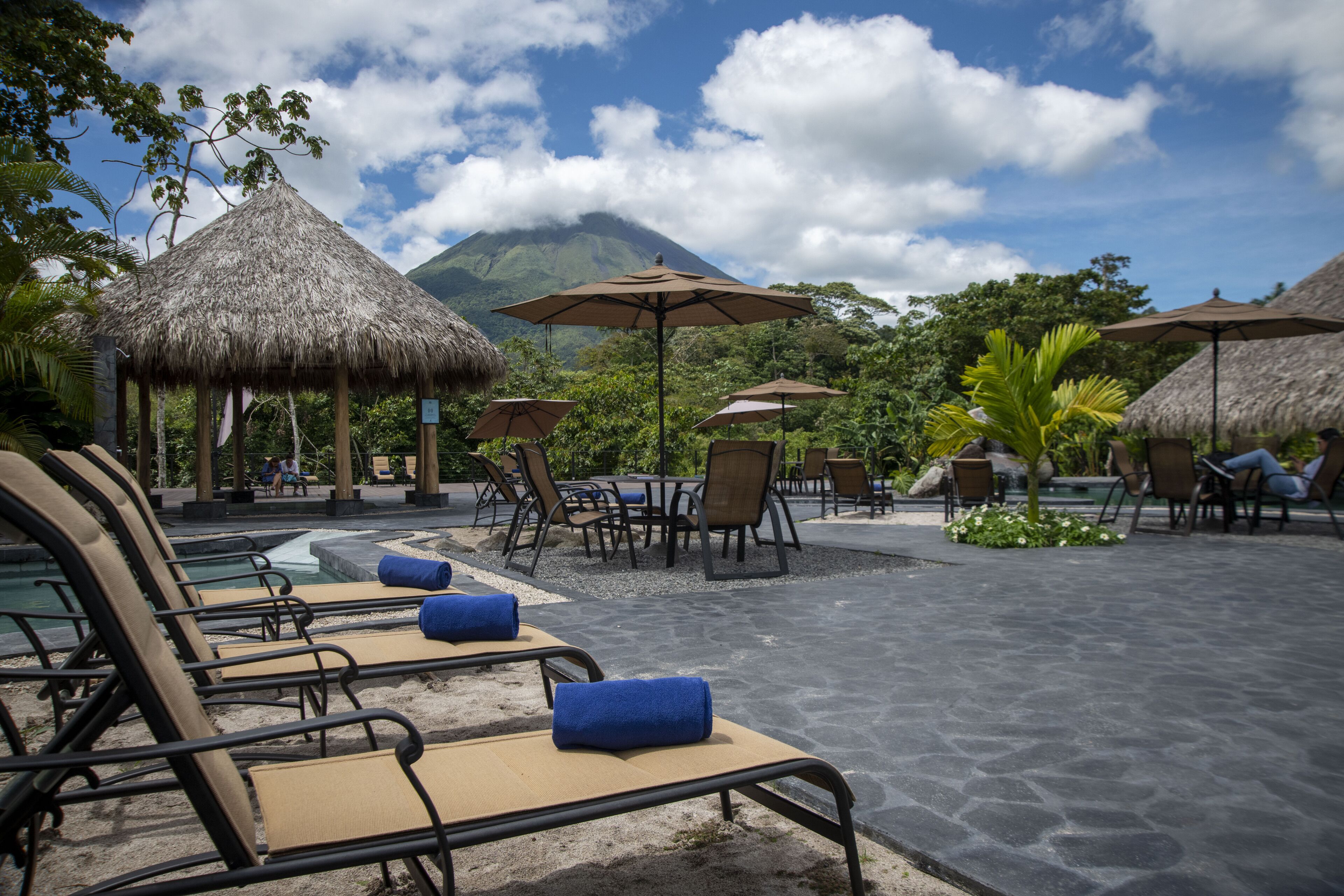 A resort with thatched-roof structures, lounge chairs, and umbrellas.
