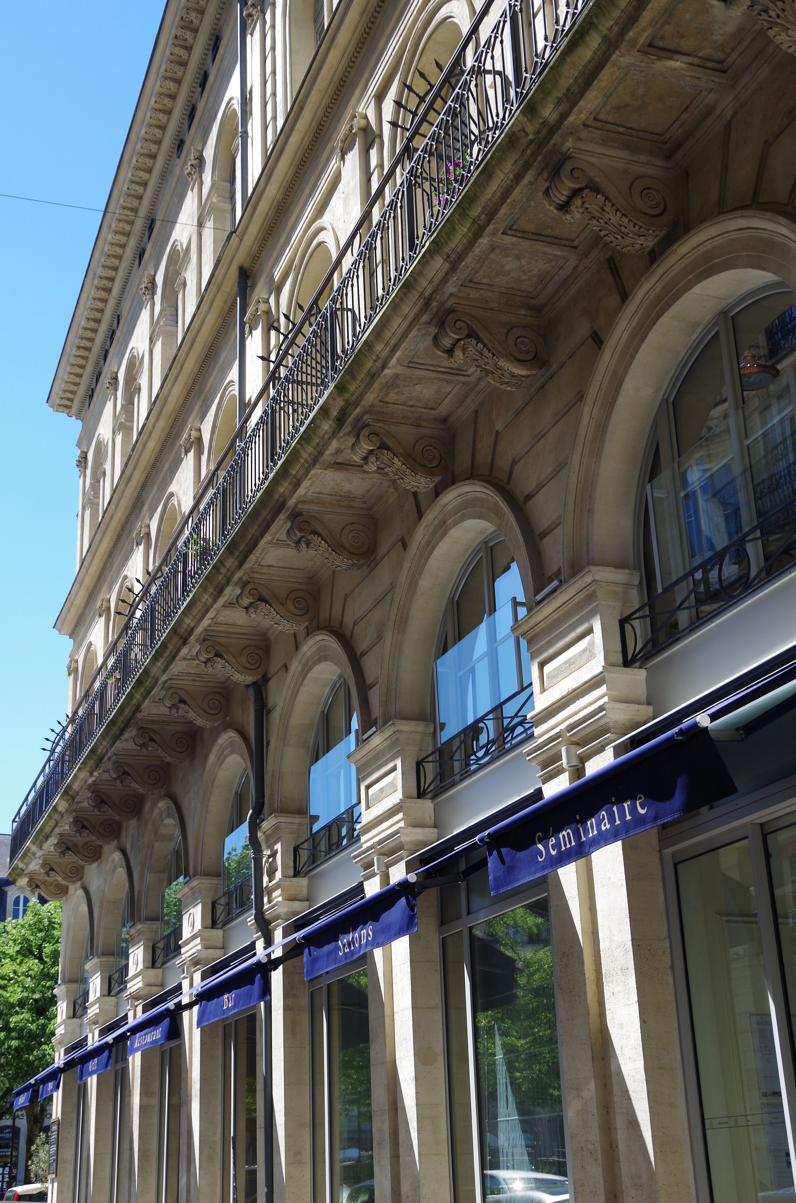 Un edificio con varios balcones, ventanas amplias y un toldo azul donde se lee la palabra 'Semaine'.