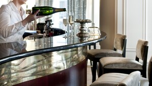 A bar area with a woman pouring a drink, a glass of wine, and a bottle on the counter. - Hôtel de Sèze (Bordeaux)
