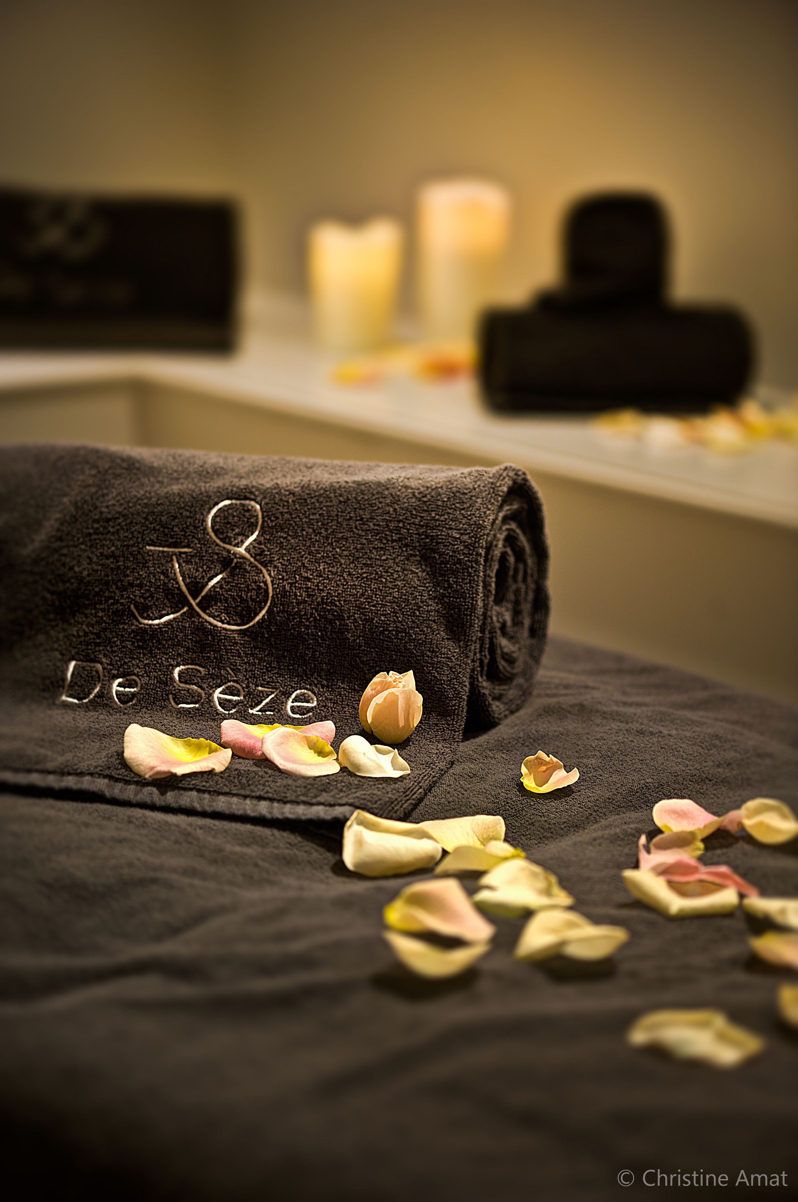 A neatly folded towel with embroidered text, placed on a surface with scattered flower petals.