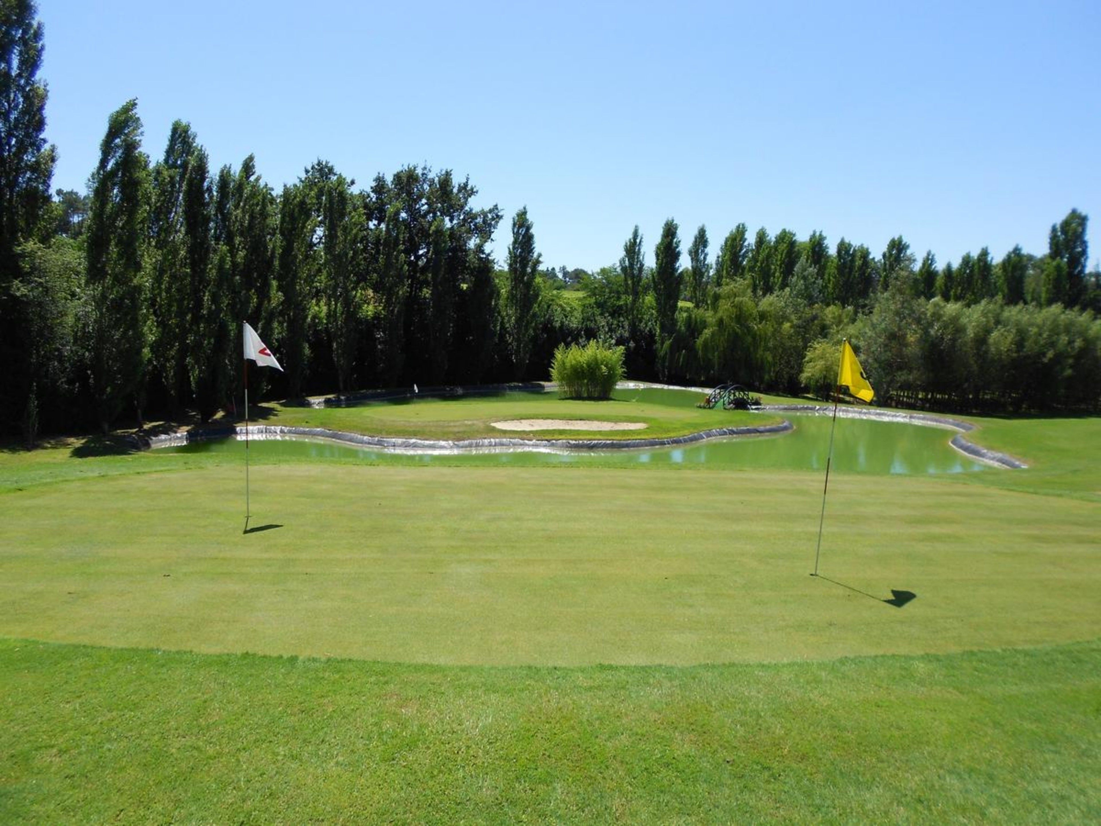 A golf course with a putting green, sand traps, and a pond.
